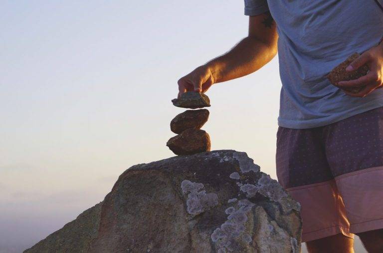 Stacking rocks at sunset, on the top of a mountain. rock pile. building. creating, meditation